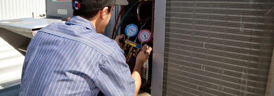 HVAC technician servicing a condenser unit in Fort Washington